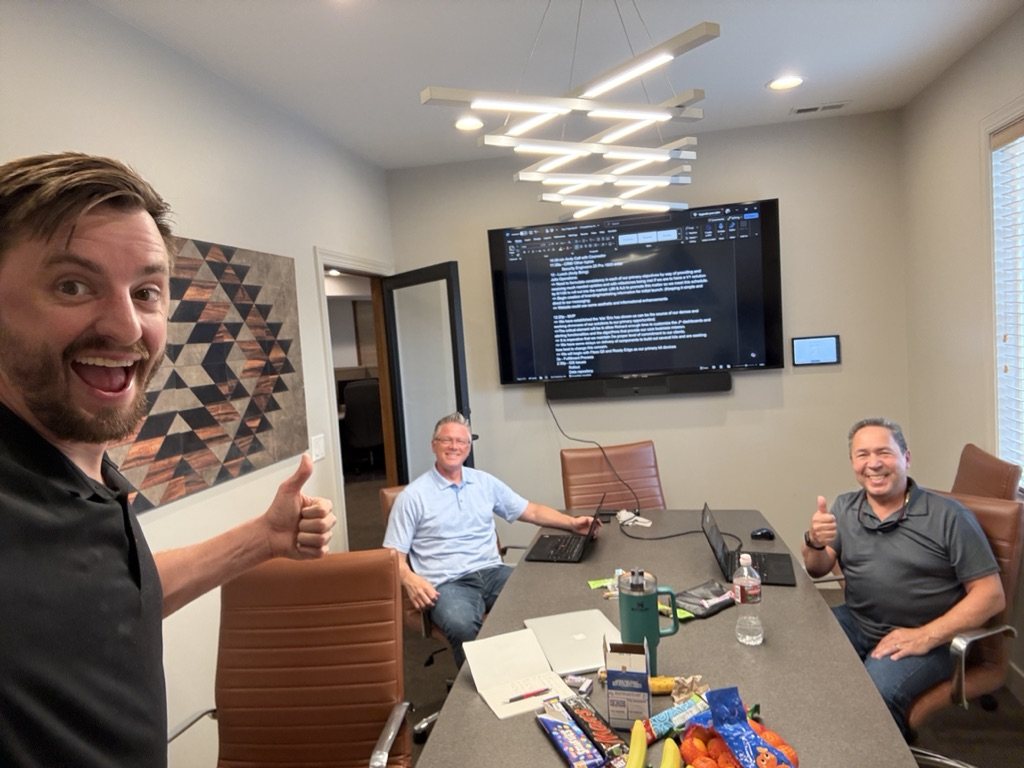 Three members of the team around a conference table, two giving a thumbs up
