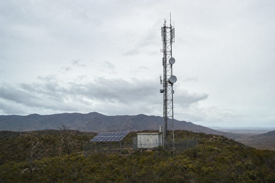 Off-grid lattice communications tower on a ridge with a ground-mounted solar array